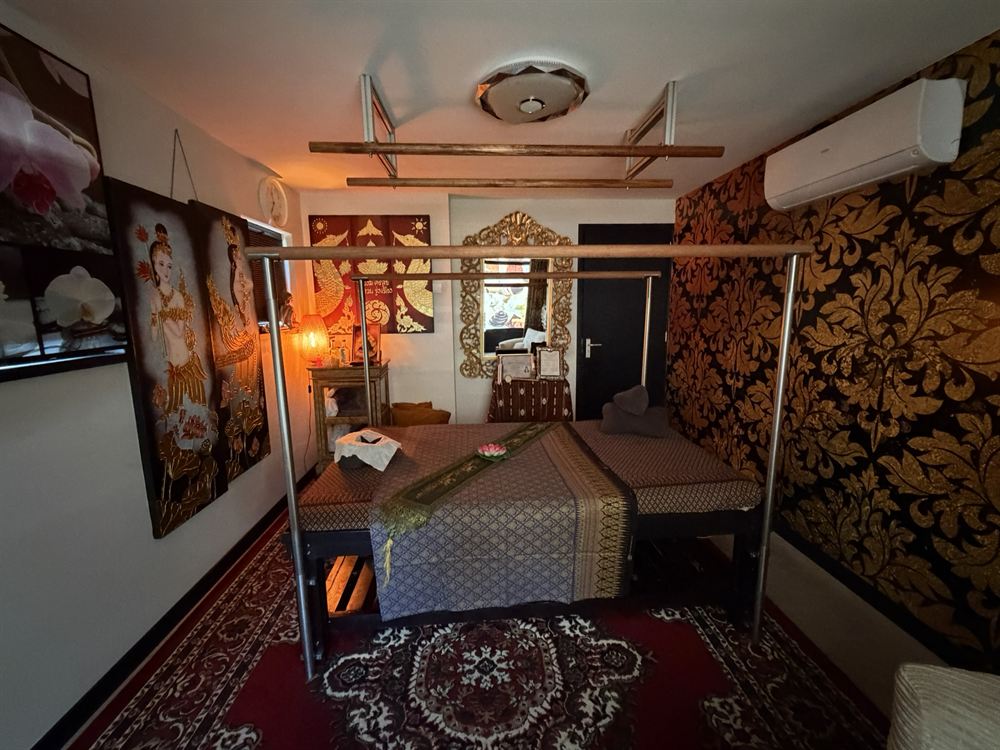 Warm verlichte behandelkamer met Thaise decoratie